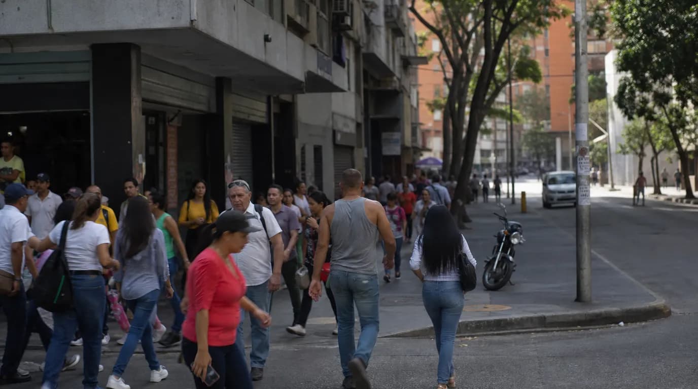 Busy commercial corner with foot traffic on an avenue in a Venezuelan city, contrasting with a quiet side street in the background