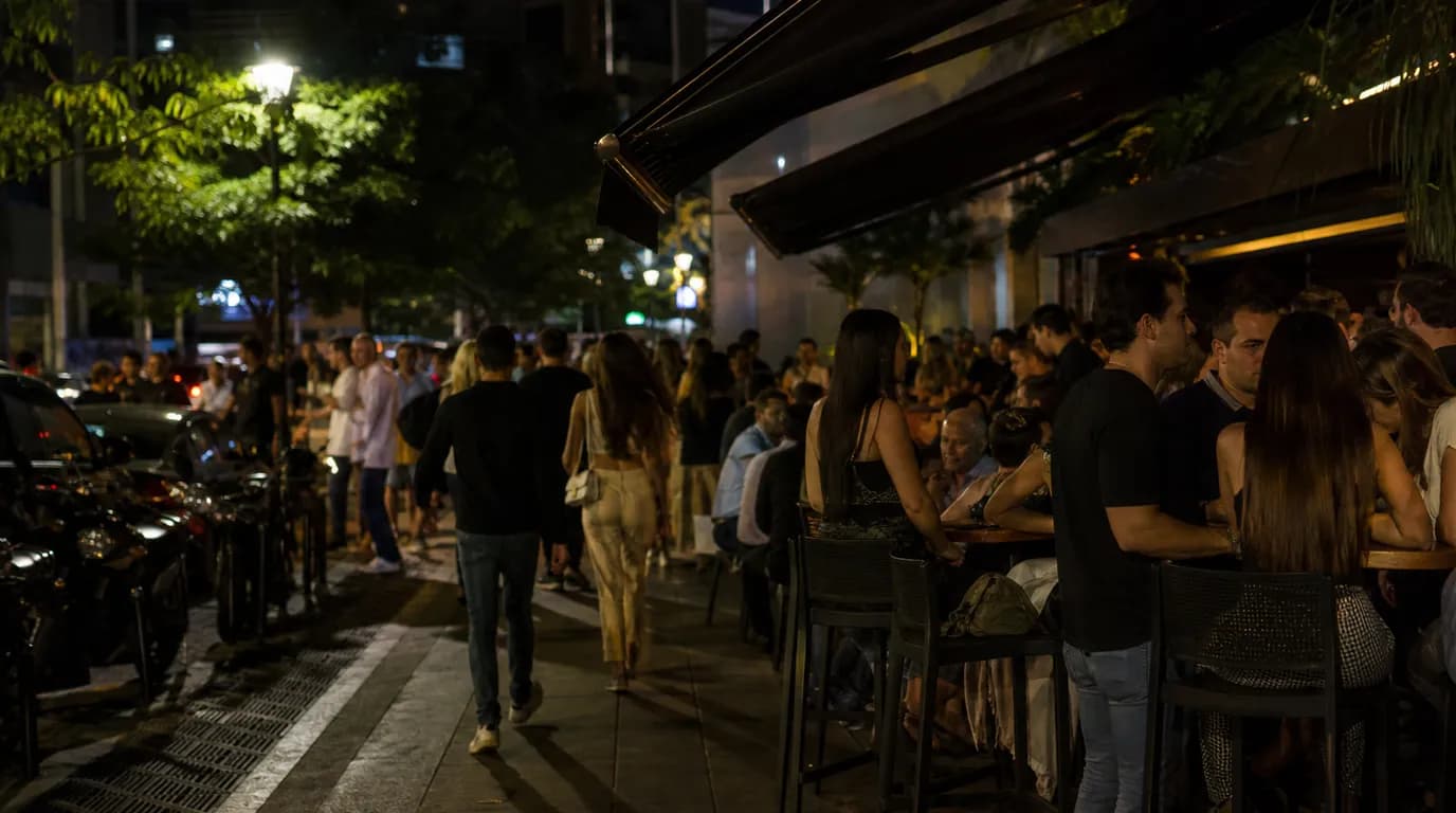 Restaurants and bars lit up at night along a Las Mercedes street in Caracas