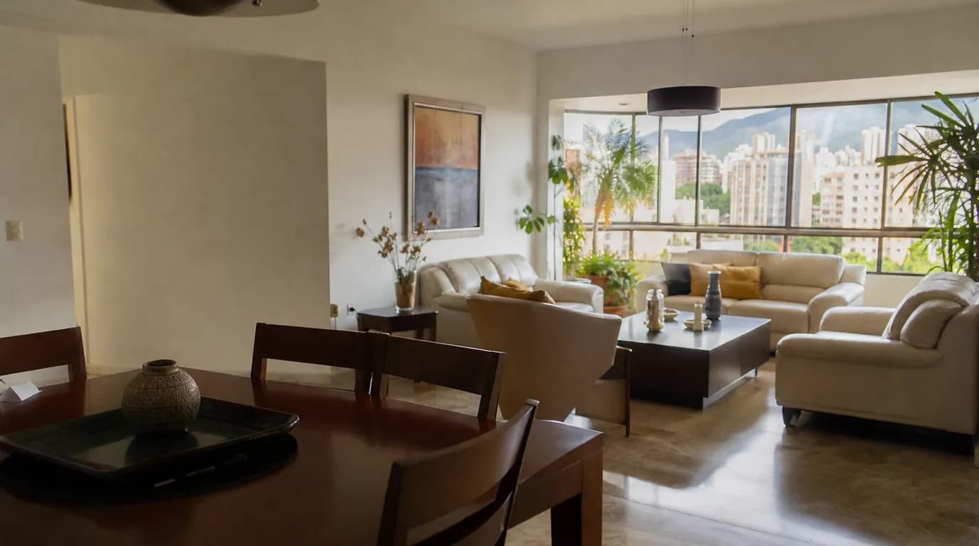 Interior luminoso y amplio de un apartamento en una ciudad del interior de Venezuela, con sala y comedor bañados de luz cálida de día